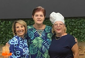 three ladies smiling for camera.  One has chef hat on.